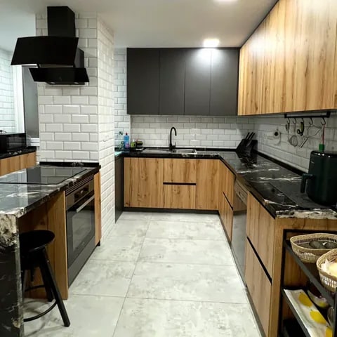 Cocina en U con mobiliario de carpintería en madera y encimera negra